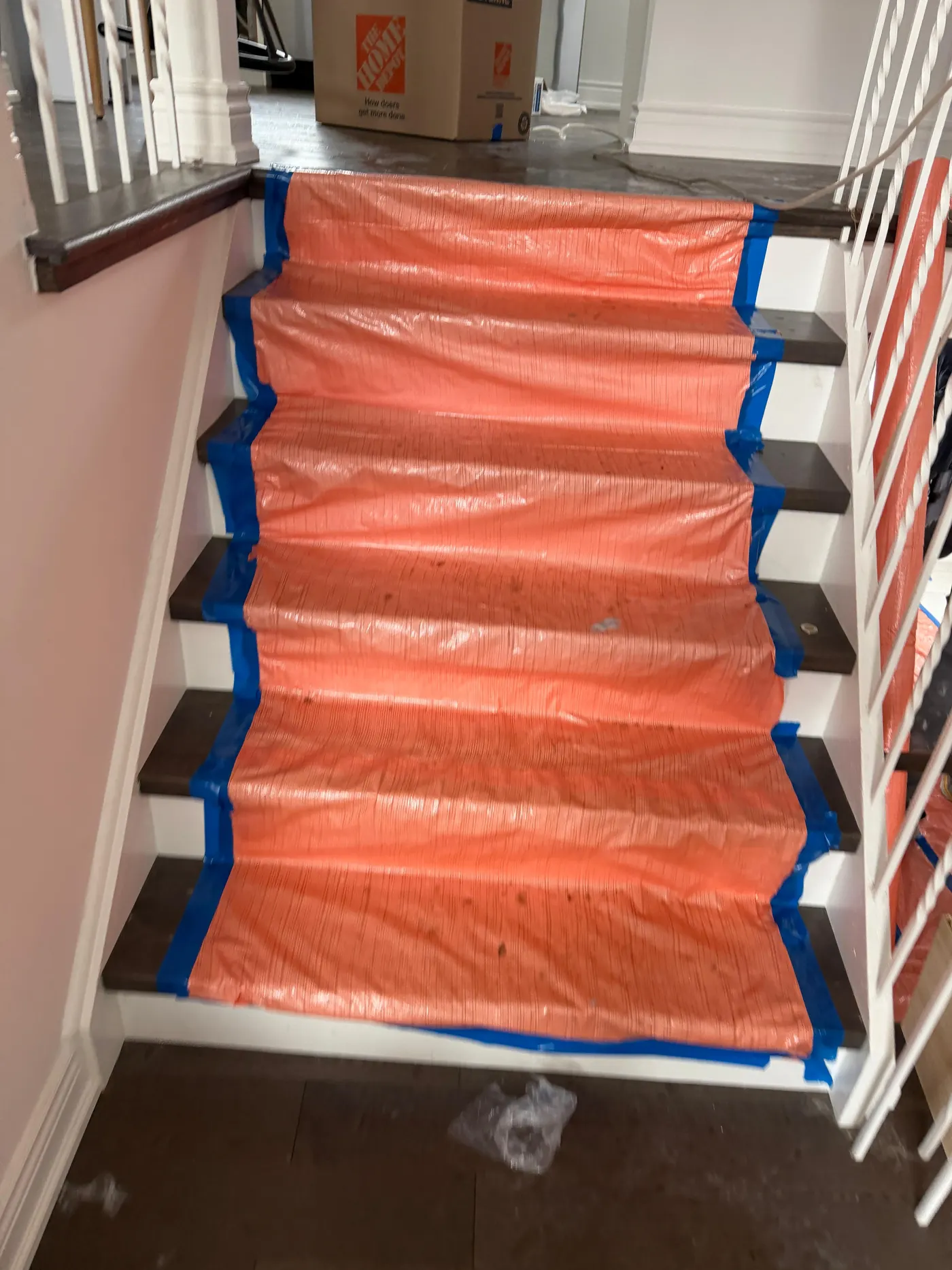 Staircase covered end to end in orange protective sheeting taped down at every tread before restoration work begins